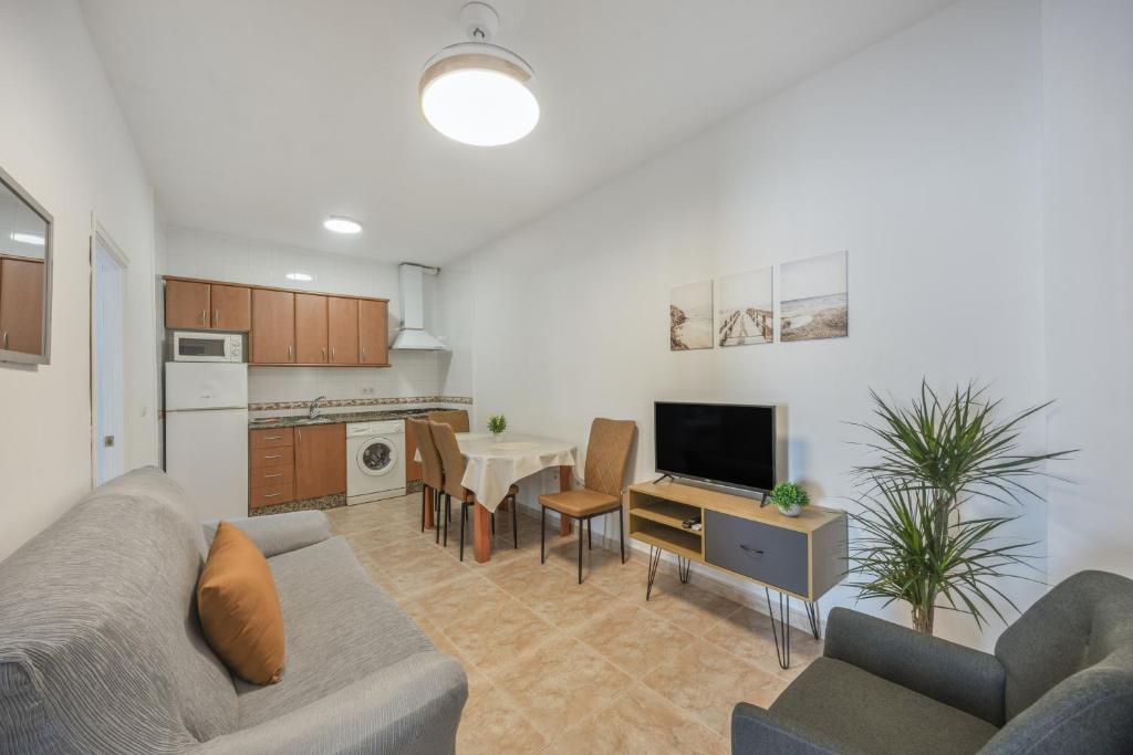 a living room with a couch and a table with a tv at Isabel Casa del Mar in Conil de la Frontera
