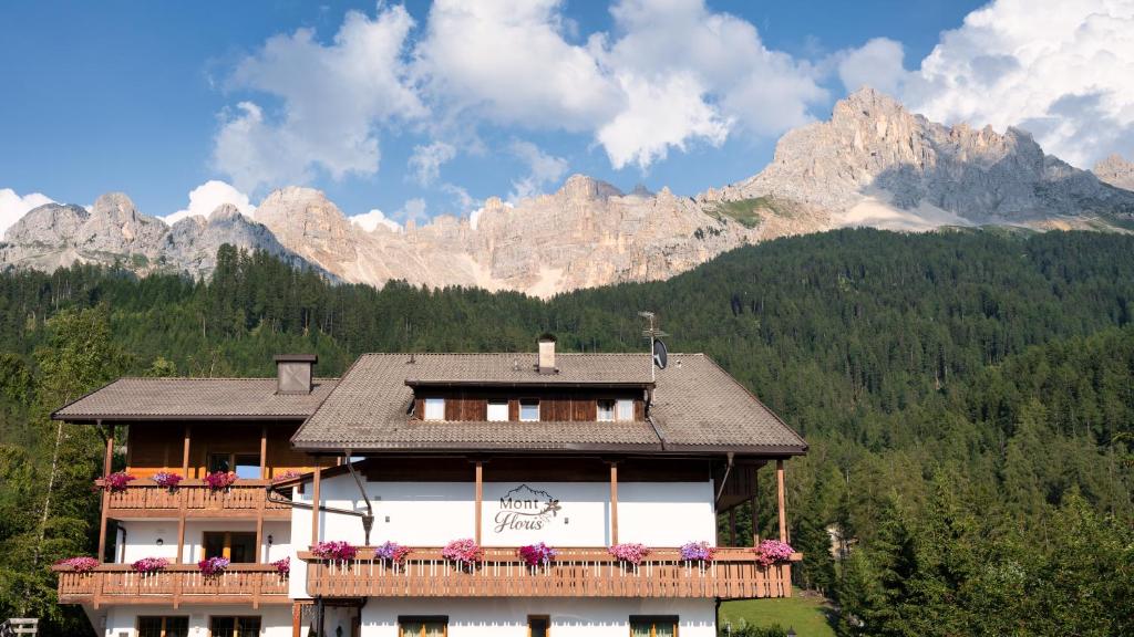 a building with a balcony with mountains in the background at Hotel Mont Floris Obereggen in Obereggen