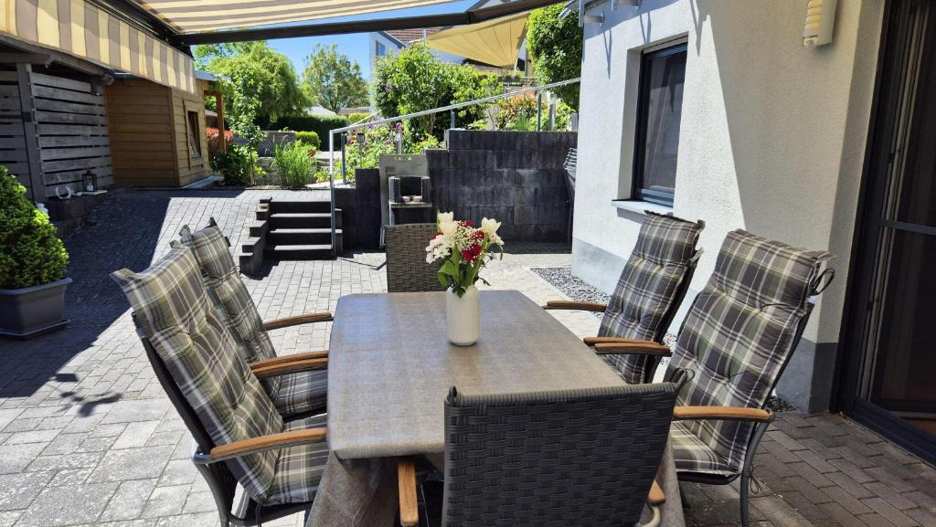 a table with chairs and a vase of flowers on a patio at Ferienwohnung BungertOase in Saarburg