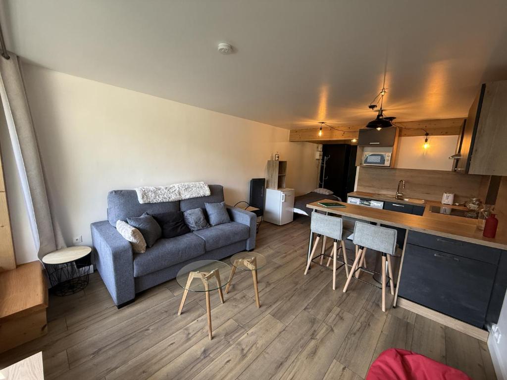 a living room with a couch and a kitchen at Studio Montagne chic centre station in Le Lioran