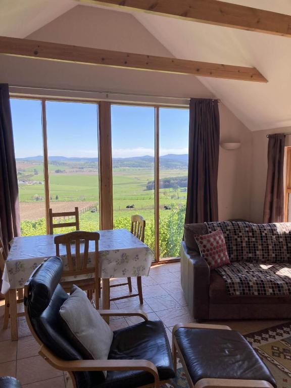 a living room with a couch and a table with a view at The Bothy in Lumphanan