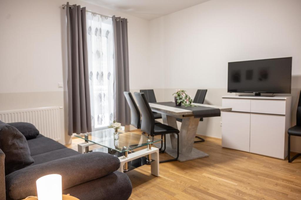 a living room with a couch and a table with a television at Paky Appartements 00322 in Bruck an der Leitha