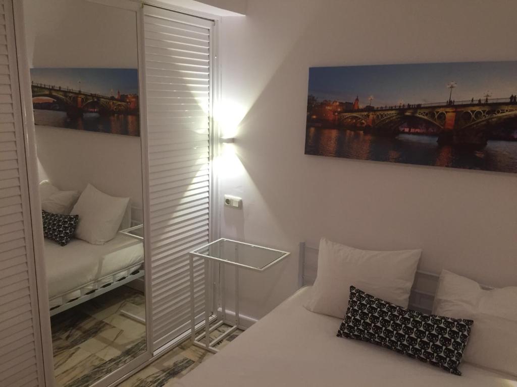 a room with a white bed and a mirror at Habitaciones Turisticas Las Brisas in Valencina de la Concepción