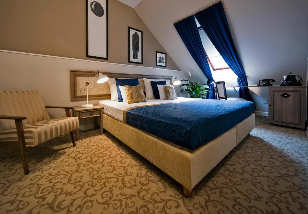 a hotel room with a bed and a chair at Hotel Jägerhorn in Zagreb