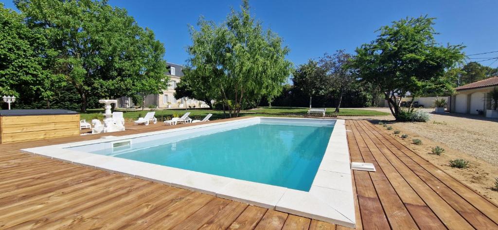 a swimming pool on a wooden deck next to a house at Suite Majorelle du Château in Gaillan-en-Médoc