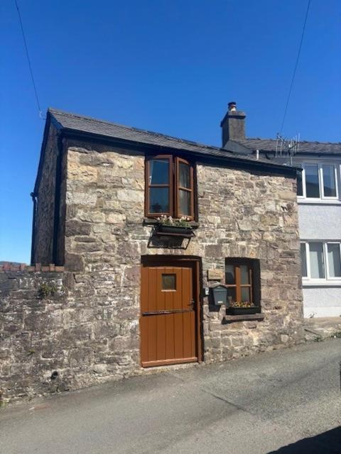 a stone building with a brown door and two windows at The Old Stable in Abergavenny