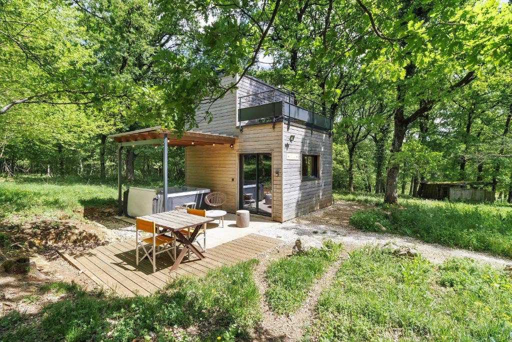 a small cabin with a picnic table in the woods at Cabane Spa - Noyers - Proche Sarlat in Jayac