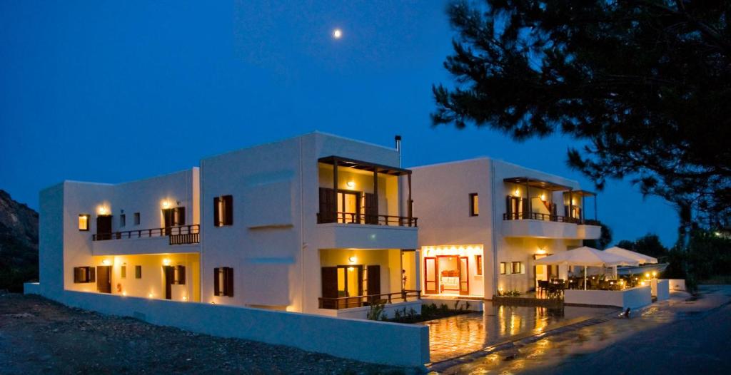 a large white building with a pool in front of it at night at Syia Hotel in Sougia