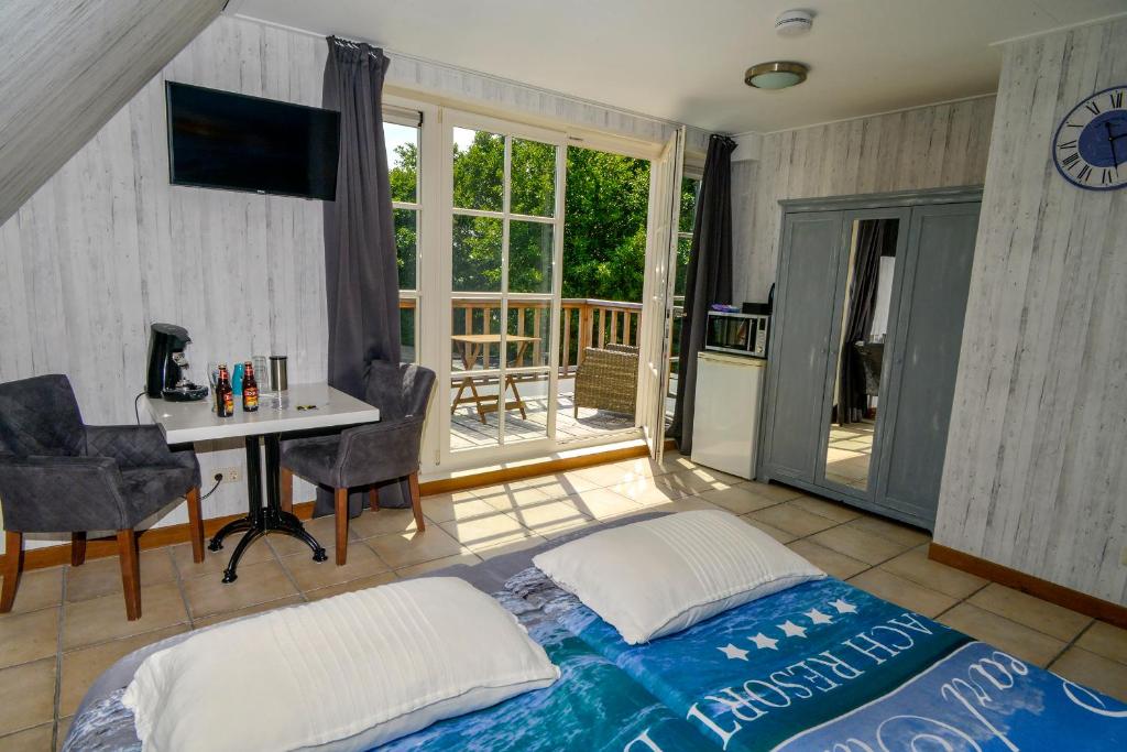 a bedroom with a bed and a desk and a balcony at Bed en Bad De Koog in De Koog