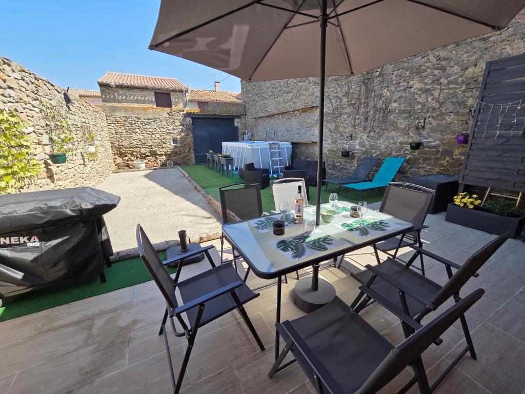 a table and chairs with an umbrella on a patio at L'Enclos de Nathalie et Jacques in Rieux-Minervois