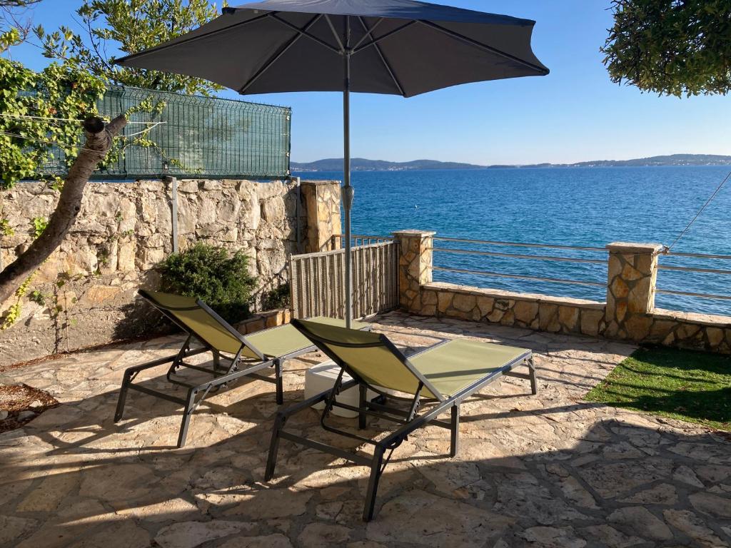 two chairs and an umbrella next to the water at House Private beach in Bibinje