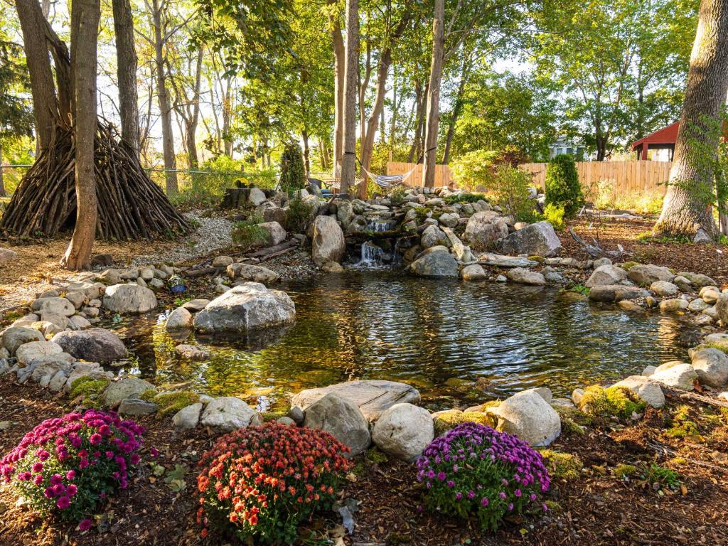 a pond in a garden with flowers and rocks at The Garden House in Saco