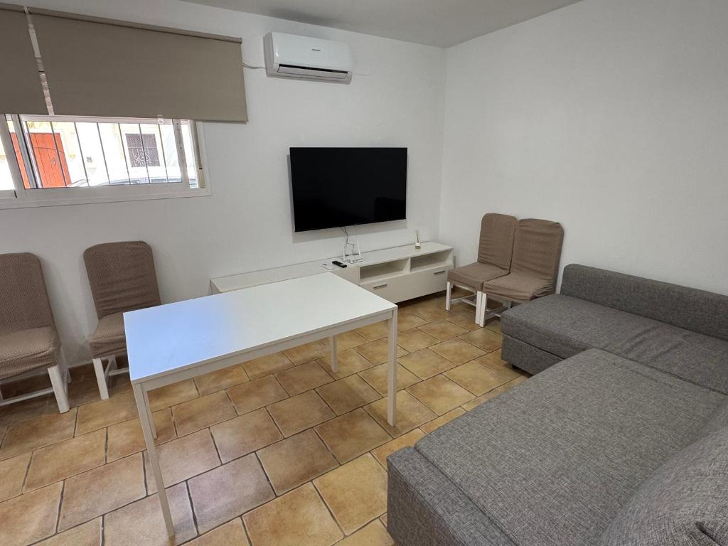 a living room with a white table and a tv at Velazquez in Lora del Río