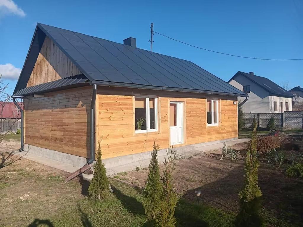 a small wooden house with a black roof at Przytulna Chata in Zamiany