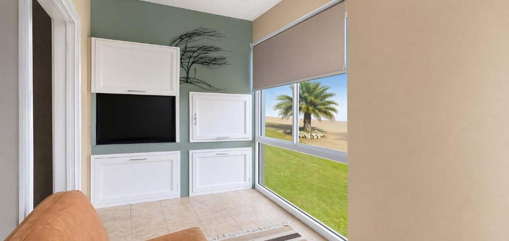 a living room with a flat screen tv and two windows at Sunset Sails 2 Apartment in Langstrand