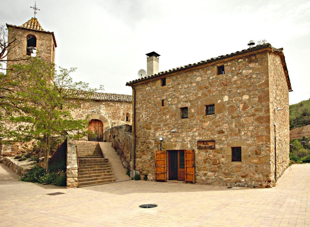 an old stone building with a staircase and a tower at L'Antic ajuntament de la Torra in La Baronia de Rialb