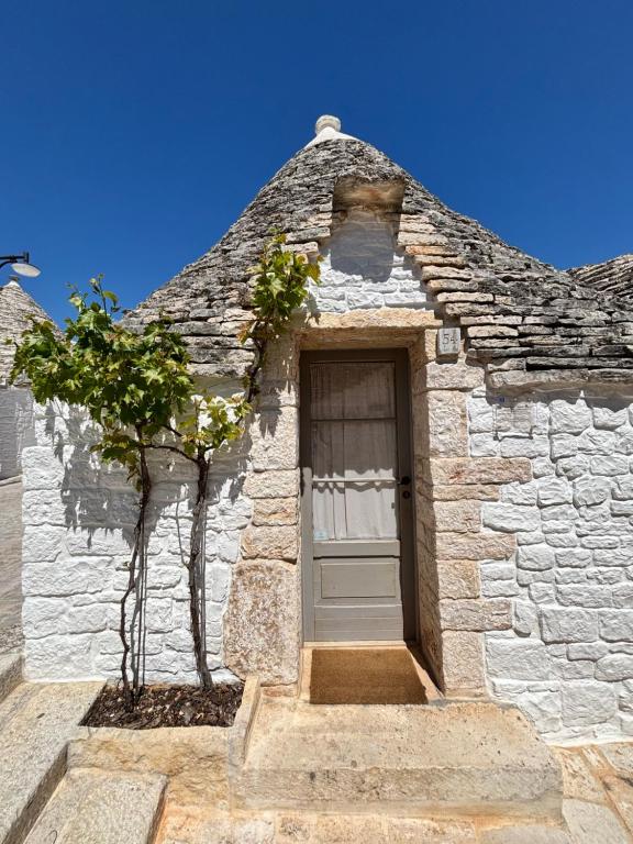 a door of a stone building with a tree next to it at Trullo Soave Suite - outdoor jacuzzi in Alberobello