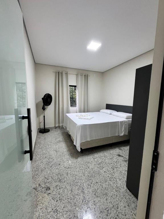 a bedroom with a white bed and a window at Casa nova e confortavel, Itabirito, MG in Itabirito