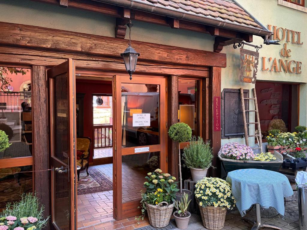 an entrance to a flower shop with a table and potted plants at Hôtel de l'Ange in Niedermorschwihr