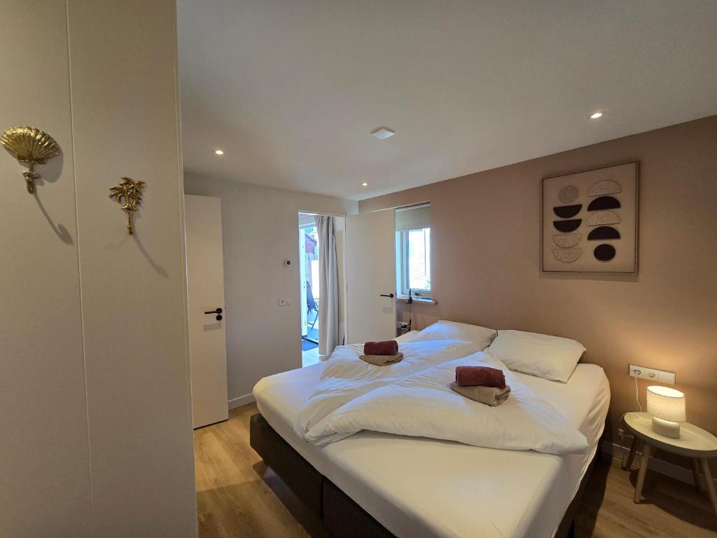 a bedroom with a bed with white sheets and towels at LÖYLY Egmond in Egmond aan Zee