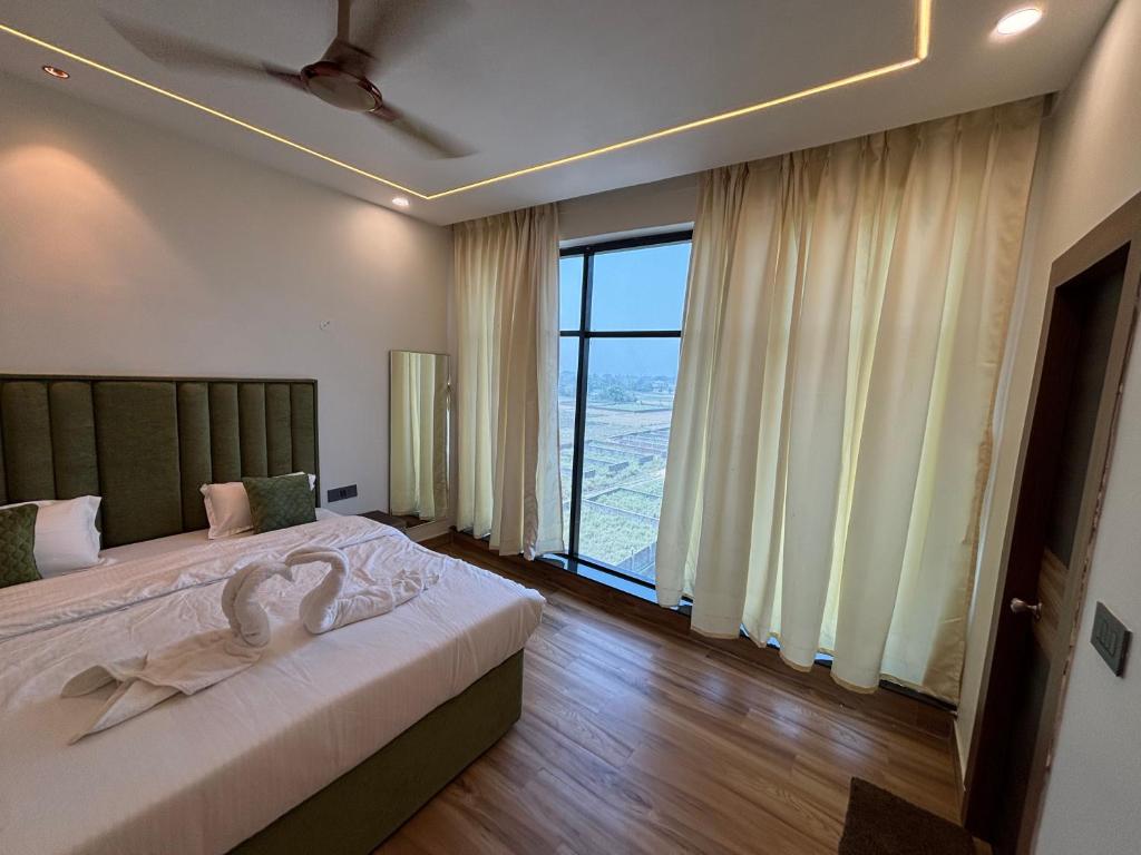 a bedroom with a bed and a large window at Hotel Picnic Garden in Patna