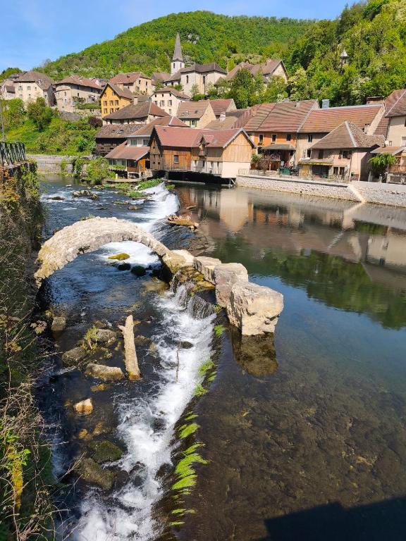 a bridge over a river with a town in the background at La maison de la Loue in Lods