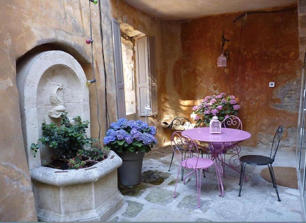 a patio with a pink table and chairs and flowers at Maison d'artiste à Bonnieux in Bonnieux