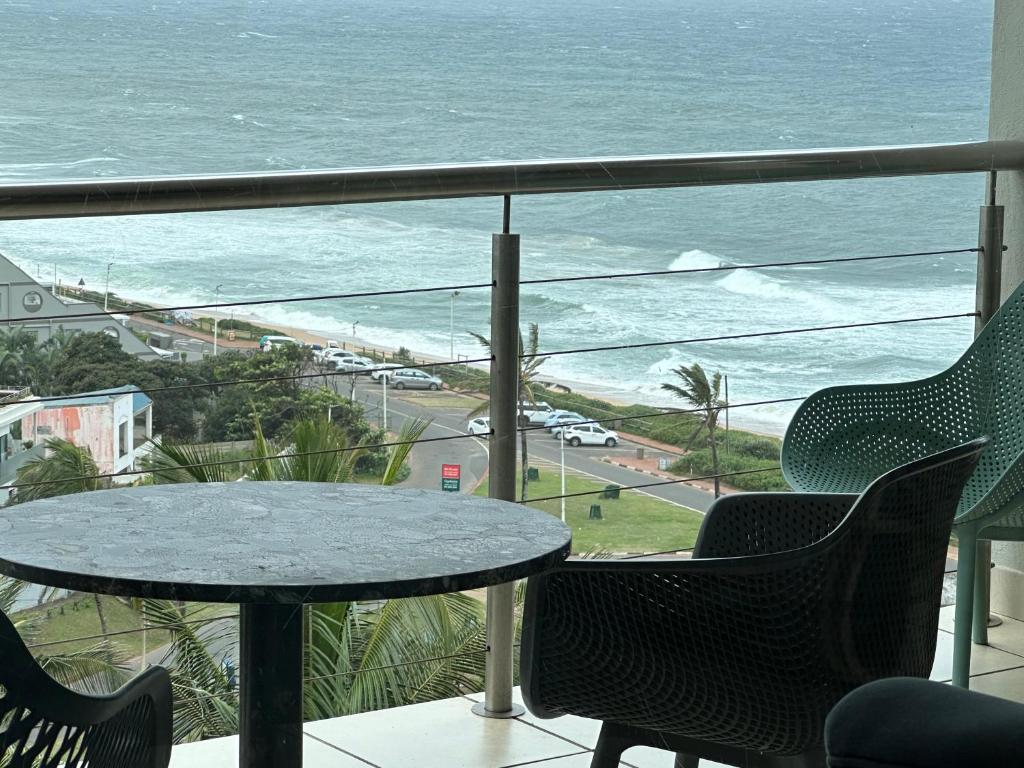 a table and chairs on a balcony with a view of the ocean at Umdloti Holiday Resort Apartment 514 - Amazing Breaker & Ocean Views in Umdloti