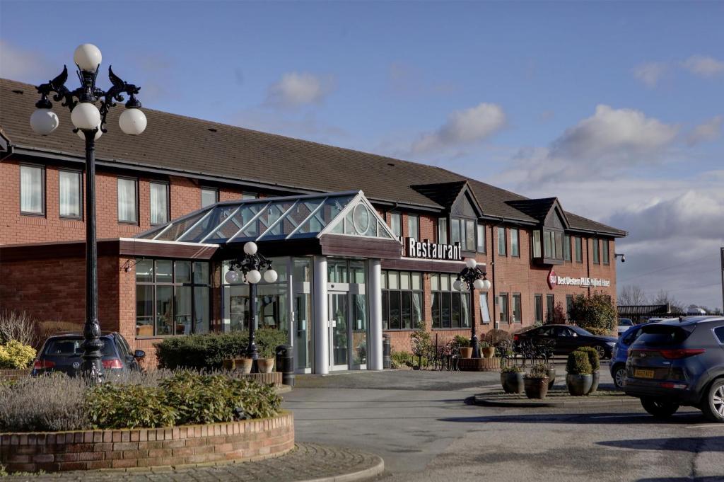 a building with a car parked in a parking lot at Best Western Plus Milford Hotel in South Milford