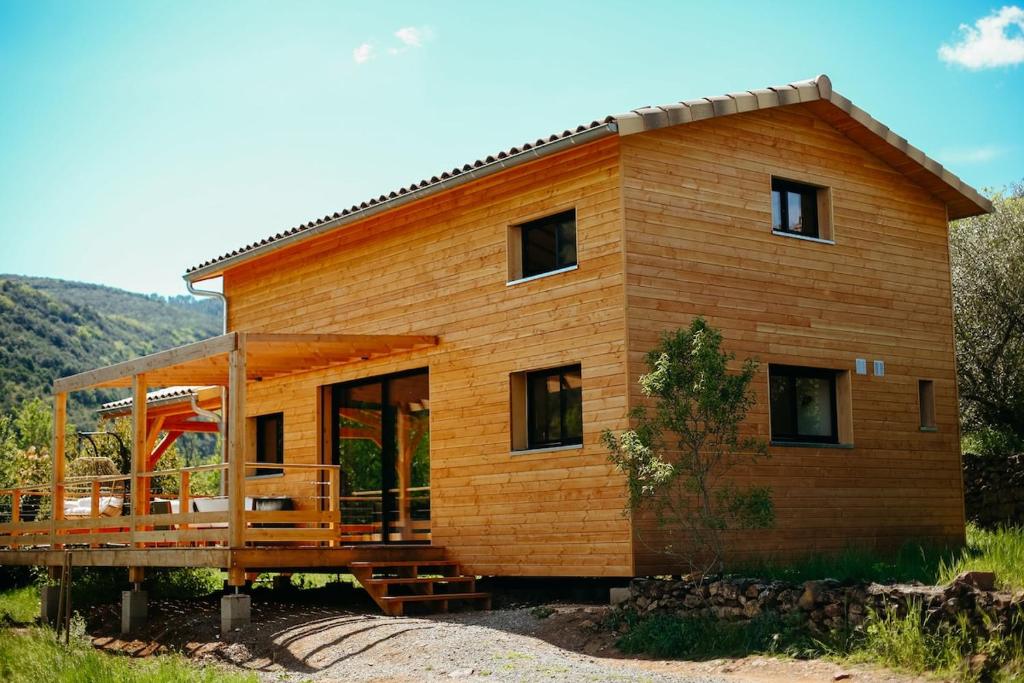 a small wooden house with a large deck at Le Chalet de la Boussonie in Les Vans