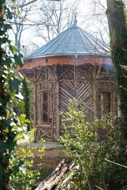 a small wooden building with a roof in the woods at Magnifique kiosque verdoyant in Semur-en-Auxois