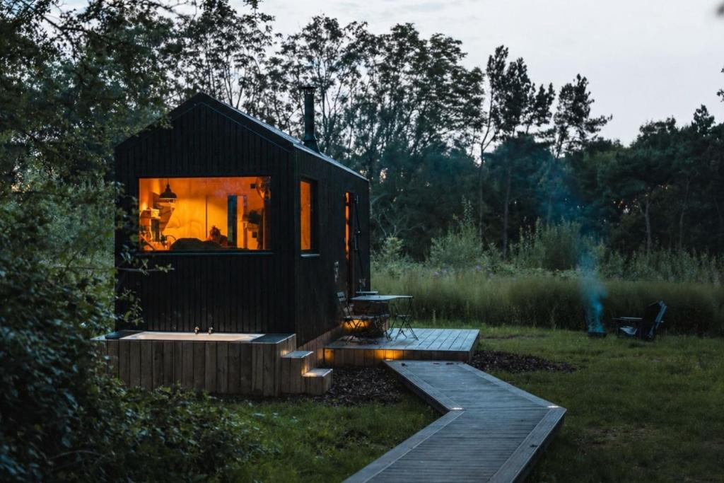 a black tiny house in the middle of a field at Adhara in Tarporley