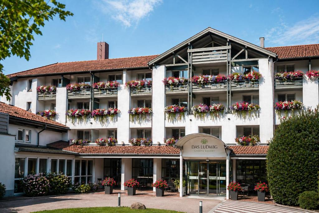 a large white building with flowers on the balconies at DAS LUDWIG Sports Resort in Bad Griesbach