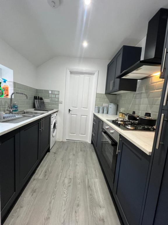 a kitchen with black cabinets and a wooden floor at Stylish Central Kettering Apartment by SJP in Kettering