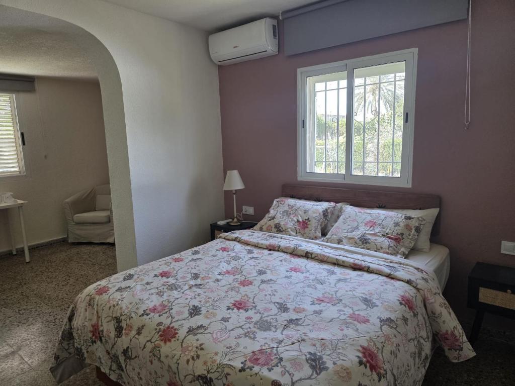a bedroom with a bed with a floral comforter at Eva luna san juan in Alicante
