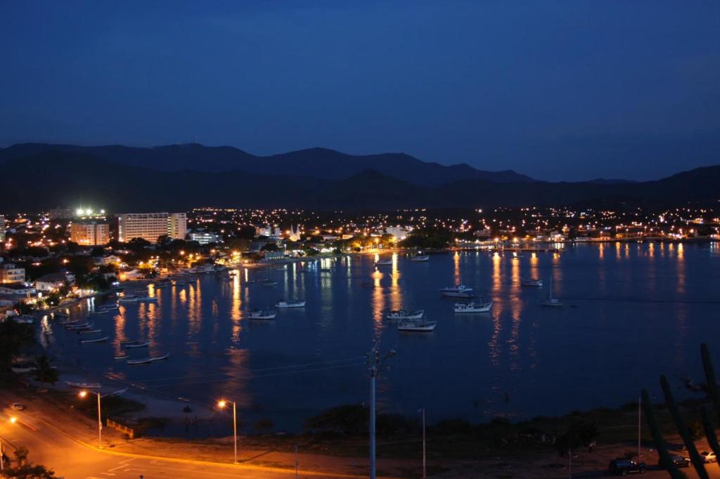 a city at night with boats in the water at Espartan Lux Juan Griego in Juangriego