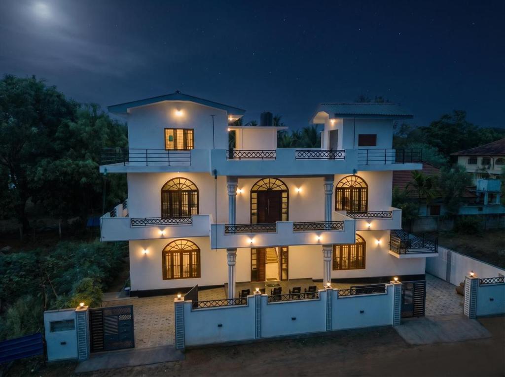a large white building with lights in the night at Vish Homes in Nallur