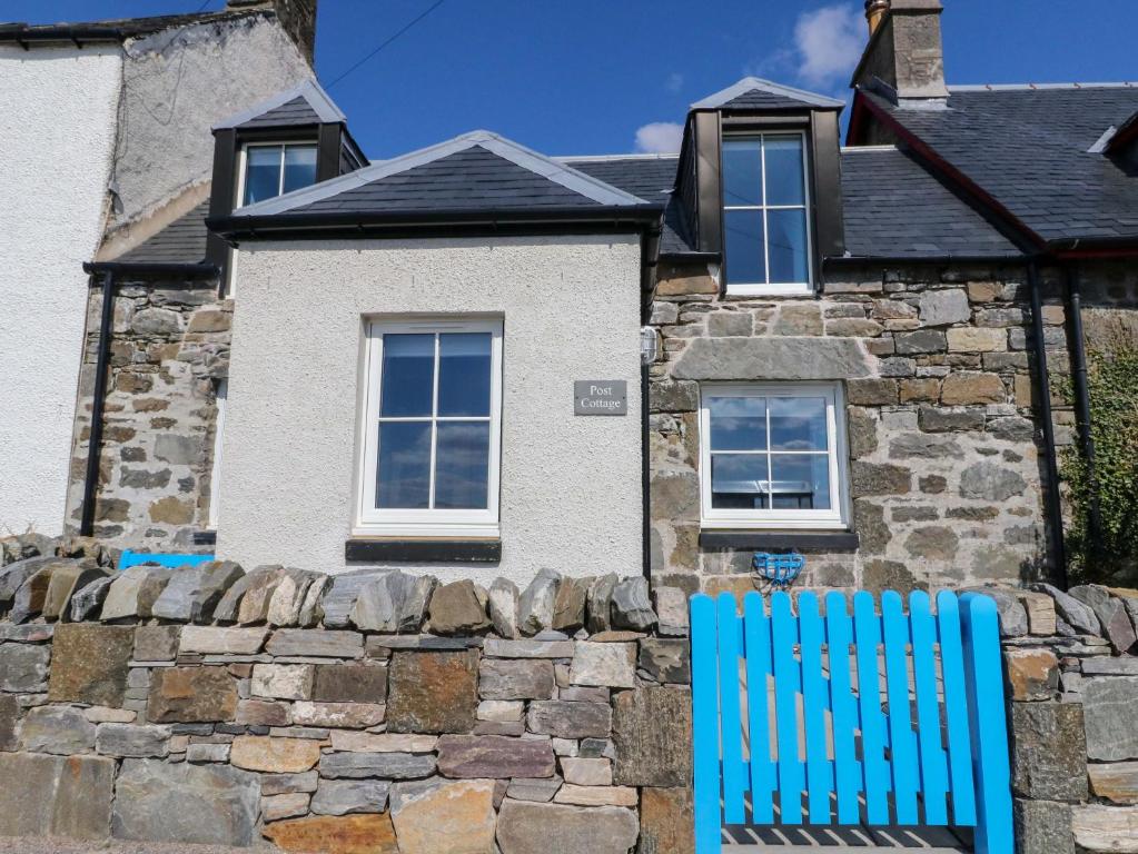 a blue chair sitting in front of a house at Post Cottage in Arisaig