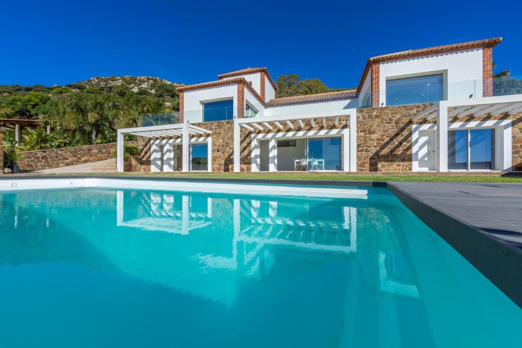 a house with a swimming pool in front of it at Villa Las Palmeras Valdevaqueros Suites, Pool & Sea Views in Tarifa