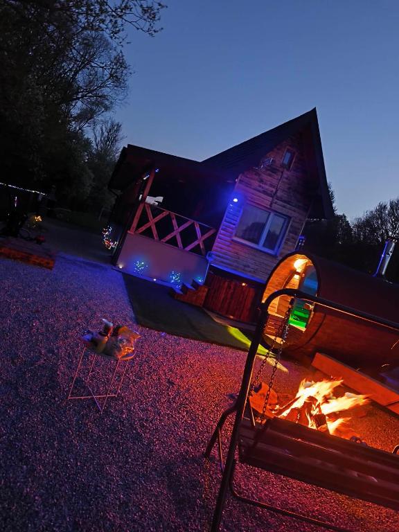 a house with a fire in front of it at night at Magiczna Chatka Nad Rzeką Bieszczady in Wietrzno