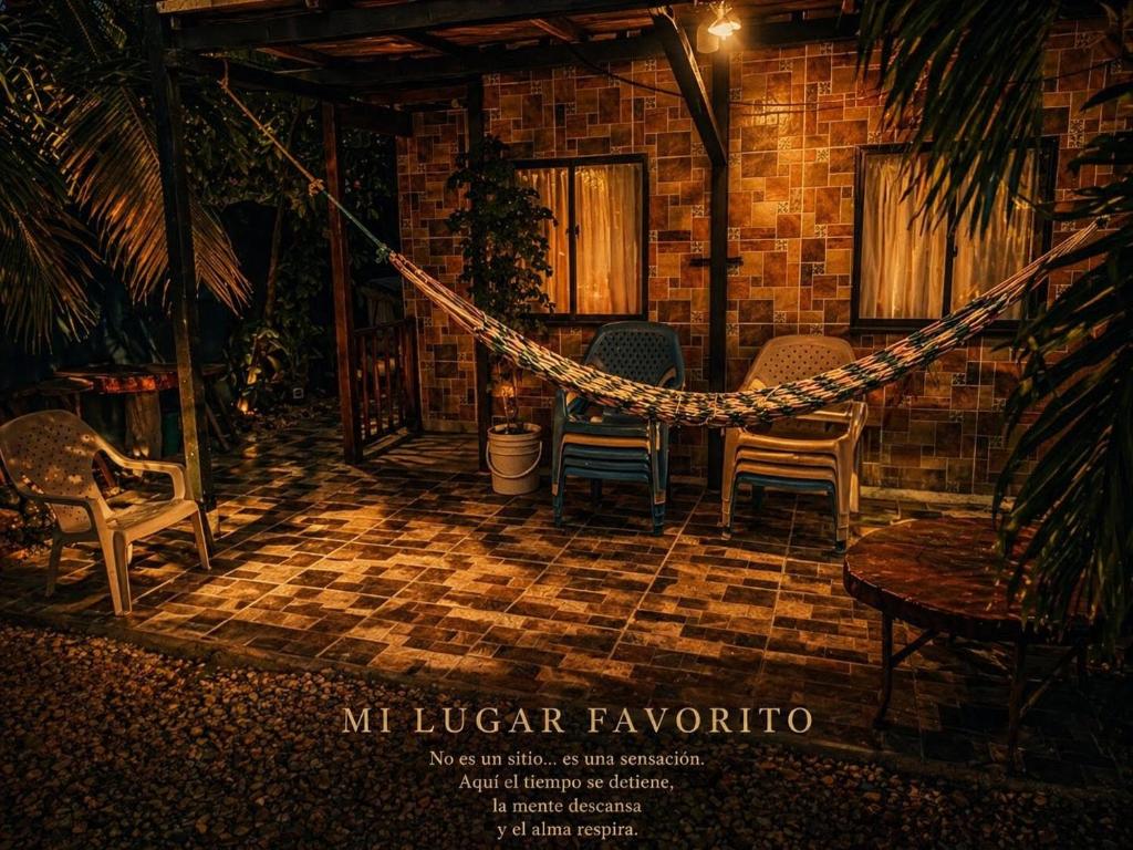 a hammock on a patio with chairs and a house at El coltejeriano in Coveñas