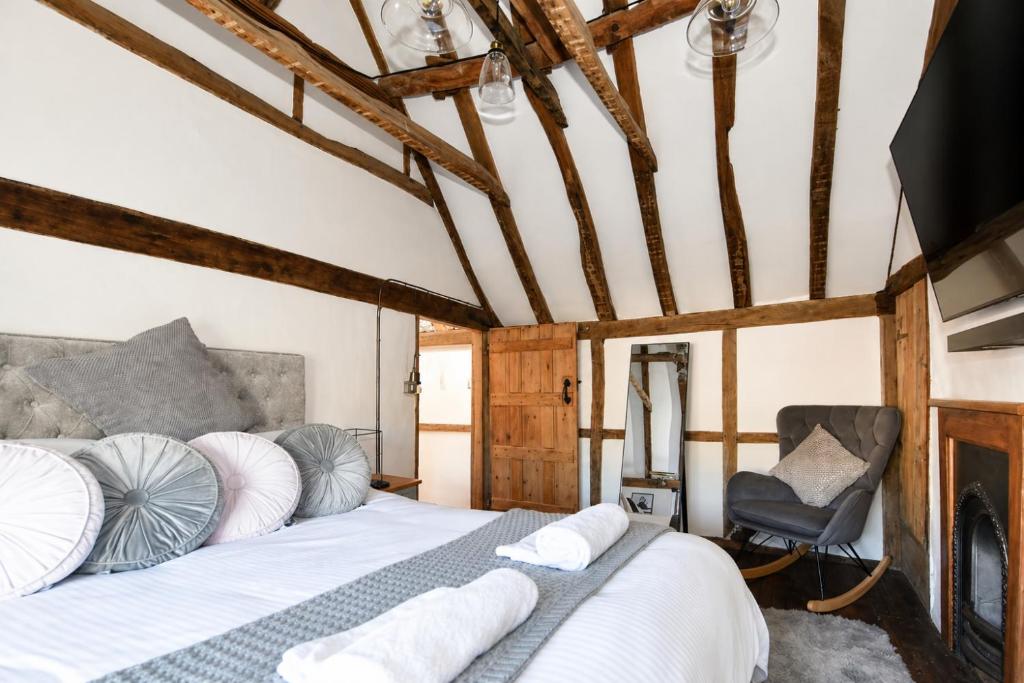 a bedroom with a bed with white pillows and a chair at Ye Olde Cottage in Crawley