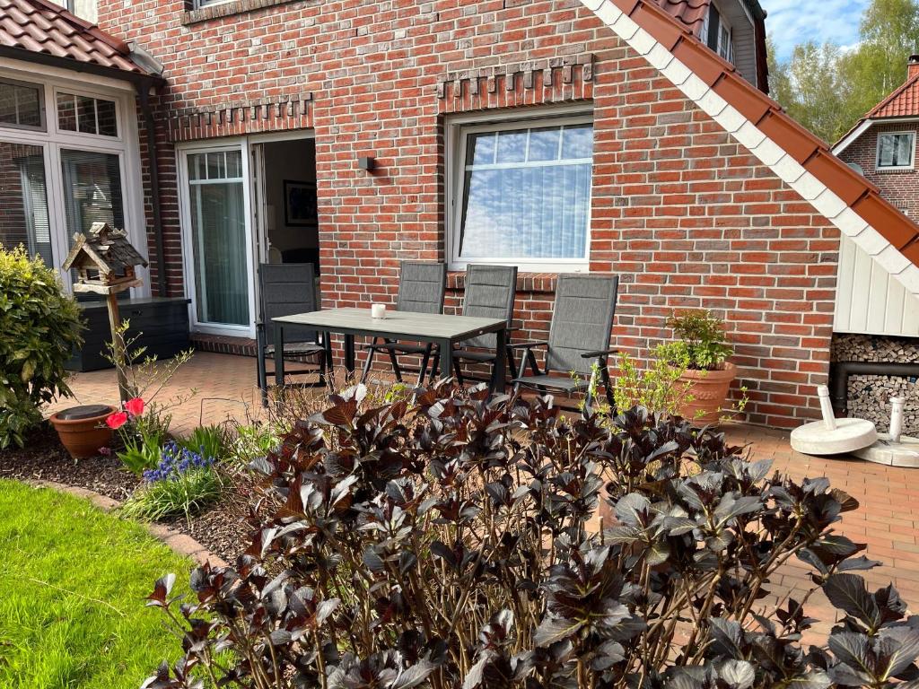 a patio with a table and chairs in front of a brick house at Ferienwohnung "Am Wichtelweg", 95176 in Rhauderfehn