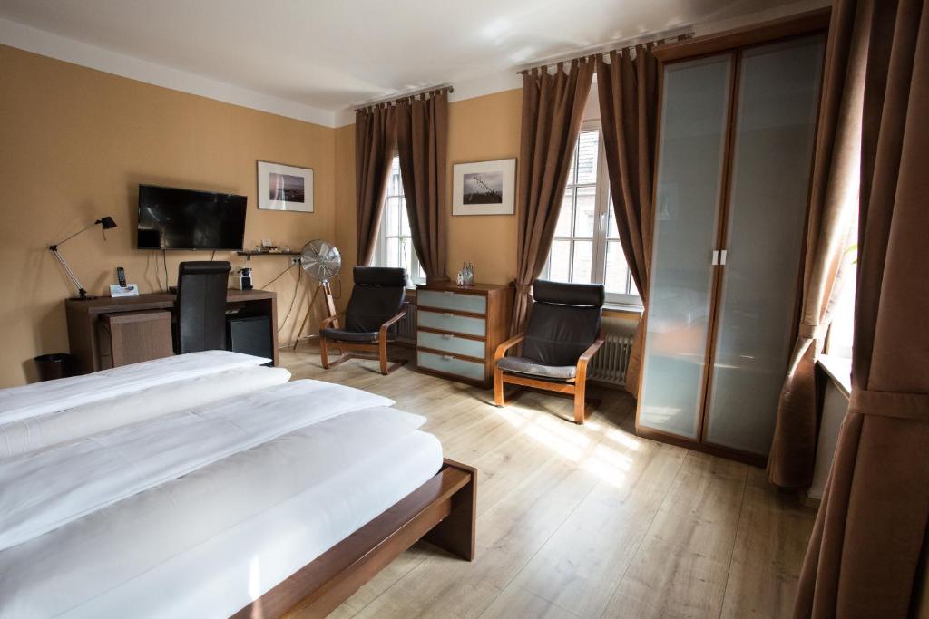 1 Schlafzimmer mit einem Bett, 2 Stühlen und einem Schreibtisch in der Unterkunft Stadthotel Jülich in Jülich