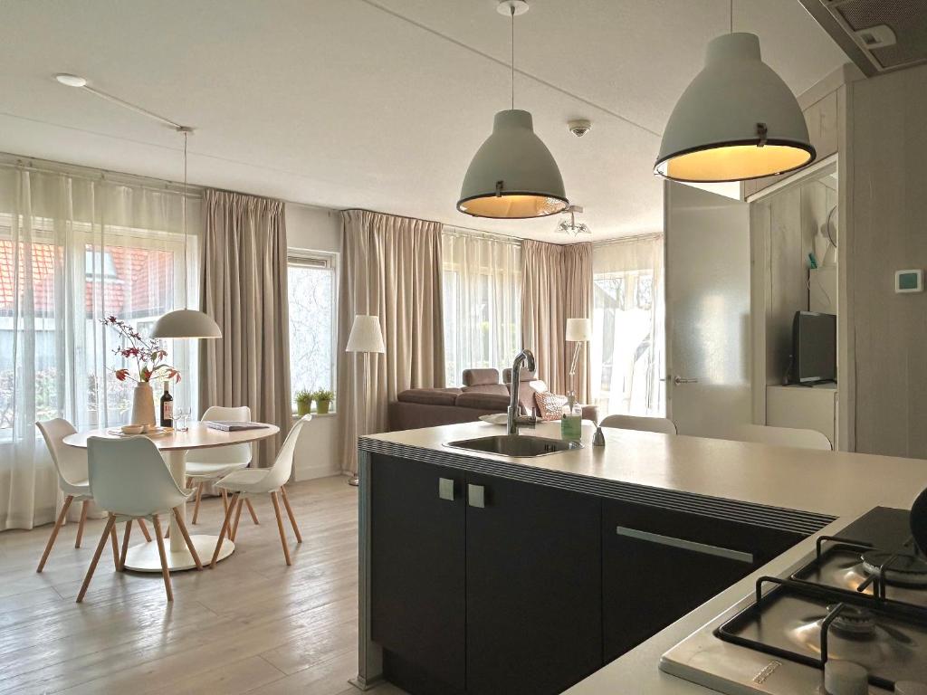 a kitchen with a sink and a table with chairs at Luxe Duinsuite in Groet
