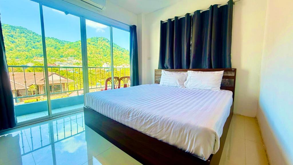 a bedroom with a bed and a large window at Silver Oaks Hotel in Patong Beach