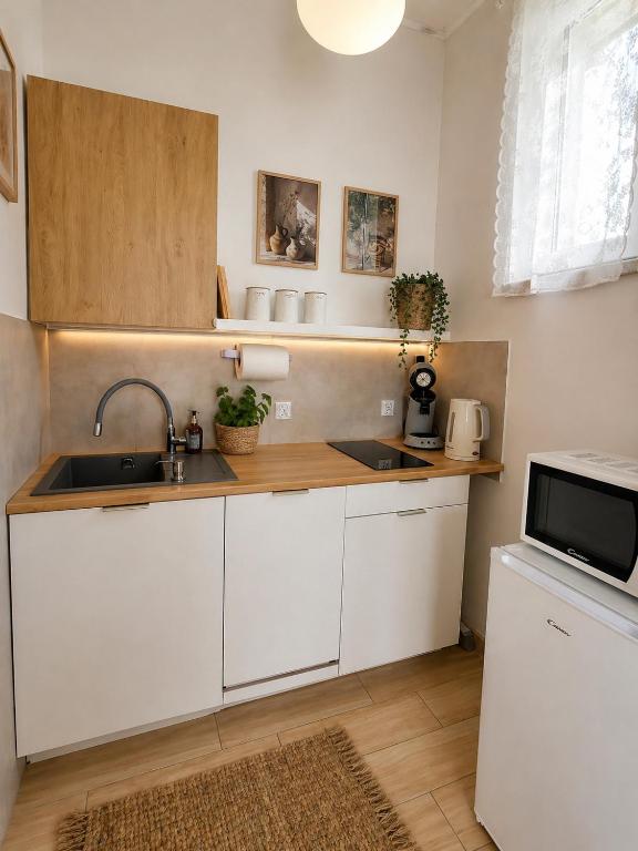 a kitchen with white cabinets and a sink and a microwave at Apartament Panorama - noclegi blisko Energylandii in Bachowice