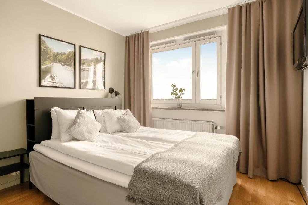 a white bed in a bedroom with a window at The Nooq Alvik - Hotel & Studios in Stockholm
