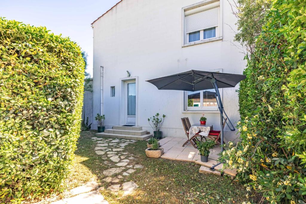 a patio with an umbrella in front of a white house at Appartement À Saint-Pierre-d'Oléron in Saint-Pierre-dʼOléron