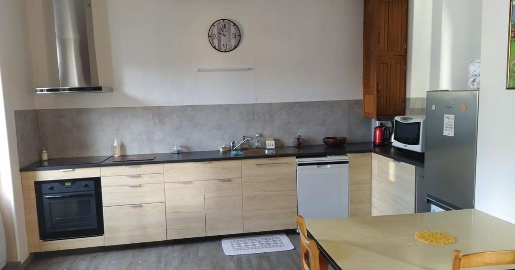 a kitchen with a sink and a refrigerator at Location maison in Neussargues-Moissac